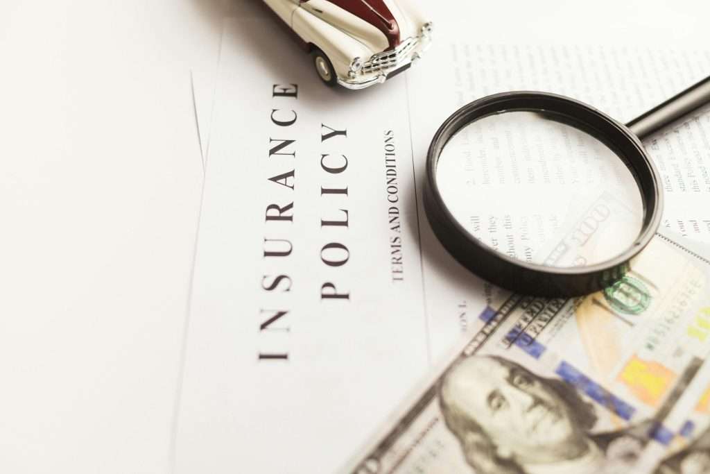 Ideal Auto Bensonhurst, pre owned car Brooklyn policy document with magnifying glass and money