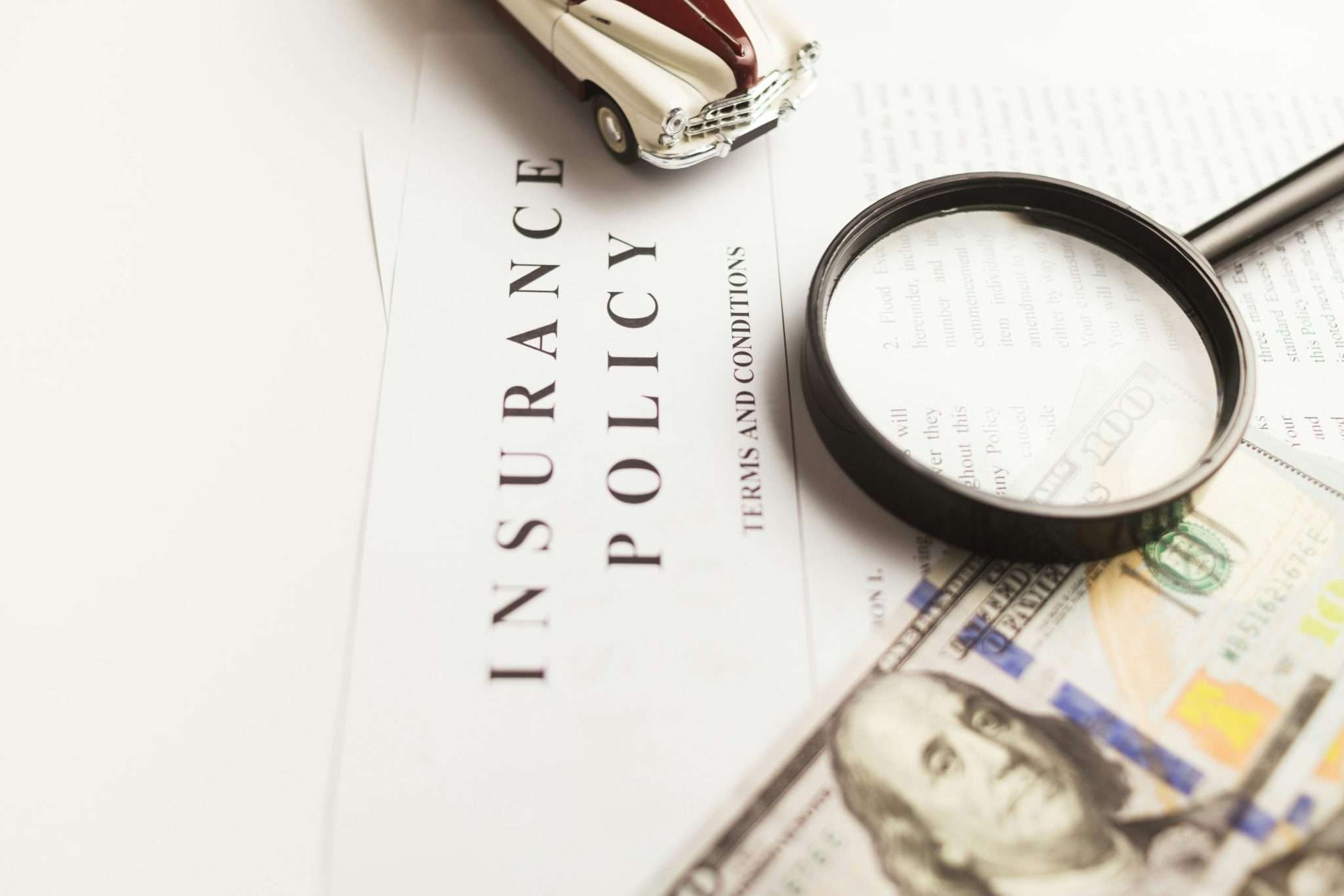 Ideal Auto Bensonhurst, pre owned car Brooklyn policy document with magnifying glass and money